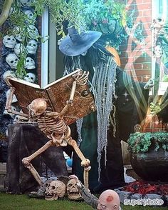 a skeleton sitting on top of a table next to a potted plant in front of a building