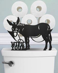 a toilet with rolls of toilet paper on top of it and a donkey cutout