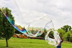 a person standing in a field with a large bubble filled kite flying through the air