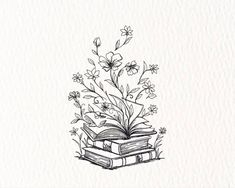 an open book with flowers on it sitting on top of a pile of books in front of