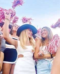 two women standing next to each other in front of a group of people wearing hats