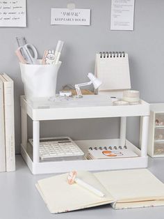 a white desk with books, pens and notebooks on it next to a pen holder