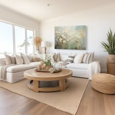 a living room filled with furniture and a large painting on the wall above it's windows