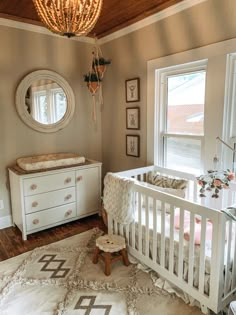 a white crib and dresser in a room with a chandelier hanging from the ceiling