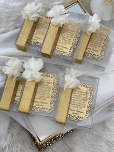 four gold and white gift boxes with flowers on them