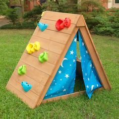 a child's play house with climbing walls and slides on the grass in front of a house