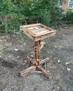 a small wooden table sitting on top of a dirt ground next to a tree trunk