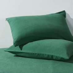 two green pillows sitting on top of a bed