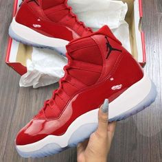 someone is holding up a red air jordan shoe