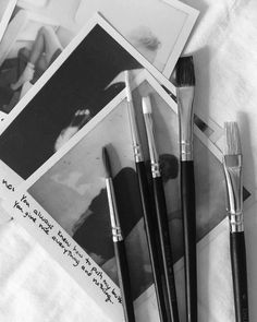 black and white photograph of artist's supplies including paintbrushes, photos and pencils