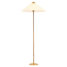 a brass floor lamp with a white shade