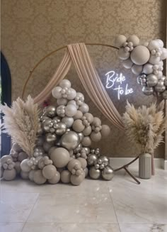 a white and silver christmas tree made out of balloons in a room with a sign that says bride to be on the wall