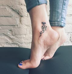 a woman's foot with a small flower tattoo on her left ankle and blue nail polish