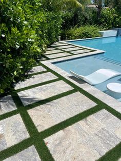 an empty swimming pool surrounded by lush green trees and grass, with lounge chairs next to it