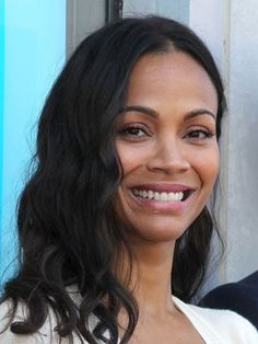 a close up of a person wearing a white shirt and smiling at the camera with long dark hair