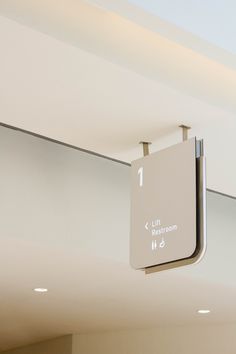 an exit sign hanging from the ceiling in a room with white walls and lights above it