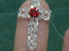 someone is holding a red and white cross brooch