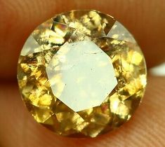 a yellow diamond is being held in someone's hand