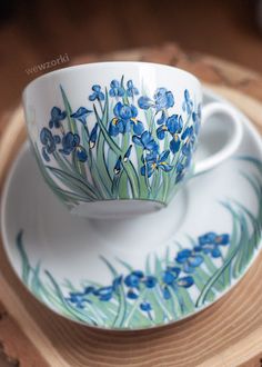 a cup and saucer sitting on top of a wooden tray with blue flowers painted on it