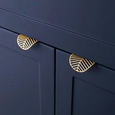 two gold leaf handles on a blue cabinet