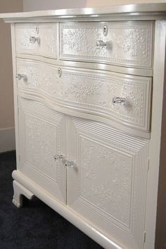 a white dresser with ornate carvings on it