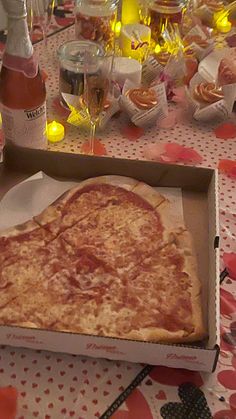 a pizza sitting in a box on top of a table next to bottles of wine