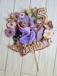 a cake topper with an image of a ballerina on it and butterflies around it