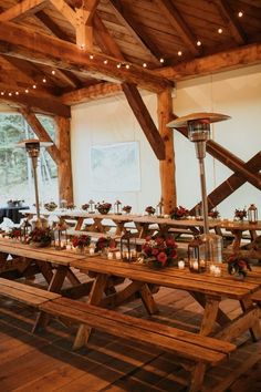 a long wooden table with candles and flowers on it in a room filled with wood beams