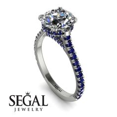 a white gold ring with blue sapphire stones on the side and an inscription segel jewelry