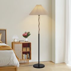 a lamp that is on top of a table next to a book shelf and bed