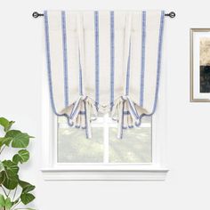 a window with blue and white stripes on the curtain, next to a potted plant