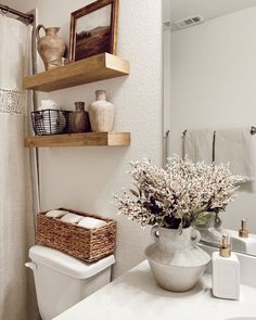 a white toilet sitting under a bathroom mirror next to a sink and a shower curtain