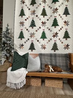 a cat is sitting on a bench in front of a christmas tree quilt