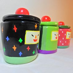 three colorful canisters sitting on top of a white table covered in polka dots