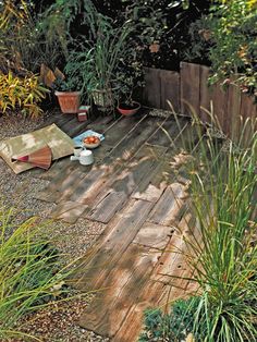 a wooden deck with potted plants and food on the ground in front of it