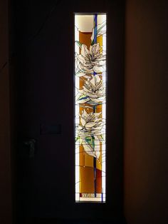 a stained glass window with flowers on it in a dimly lit room by a door