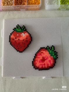 two plastic strawberries sitting on top of a table next to some bead sprinkles