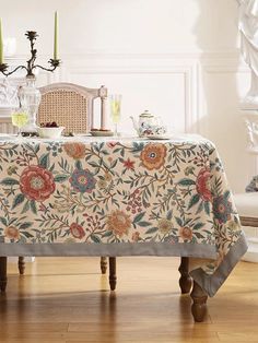 a table covered with a flowered cloth and two candles sitting on top of it