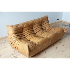 a brown couch sitting on top of a hard wood floor next to a white wall