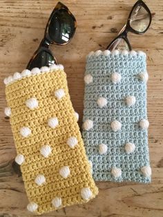 two crocheted glasses cases sitting on top of a wooden table