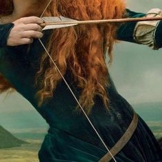 a woman with long red hair holding an arrow