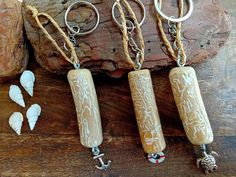 three key chains with charms attached to them sitting next to a rock and seashells