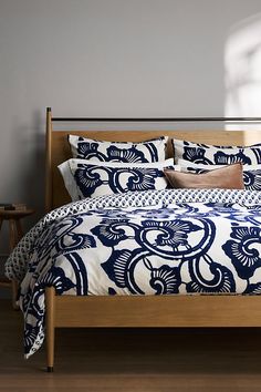 a bed with blue and white bedspread, pillows and pillow cases on it