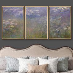 three paintings hang on the wall above a bed with pillows and throw pillows in front of it