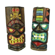 two wooden tiki masks with different designs and colors on the faces are standing side by side