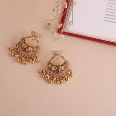 Description : These lotus chandbali earrings with antique gold polish are crafted to attract attention. It has a beautiful design with kempu and CZ stones paired with drop pearl beads in a depicting nakshi arrangement. Details & Specifications: Materials used: Brass Alloy with Antique Plating Weight - 21.45 gm Length - 5 cm Make it custom : Want to make it a custom Earrings ? Sure! Reach out to us at support@tarinika.com and we’ll be happy to make possible modifications at no extra cost. Feel fr Cheap Gold Bollywood Chandbalis, Luxury 22k Gold Traditional Chandbalis, Festive Chandbali Earrings With Peacock Design, Festive Peacock Chandbali Earrings, Festive Peacock Design Chandbali Earrings, Bollywood Style Kundan Chandbalis In Dual-tone, Bollywood Style Dual-tone Kundan Chandbalis, Dual-tone Chandbalis For Diwali Festivities, Wedding Kundan Chandbalis With Peacock Design