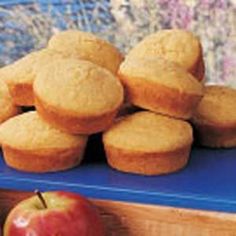 a pile of muffins sitting on top of a blue tray next to an apple