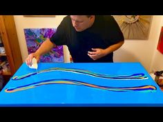 a man is painting a blue table with multicolored lines on the top and bottom