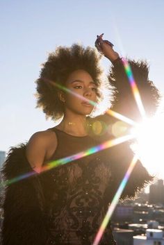 a woman with an afro standing in front of the sun