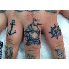 a person's hand with tattoos on it and an anchor, ship wheel and compass